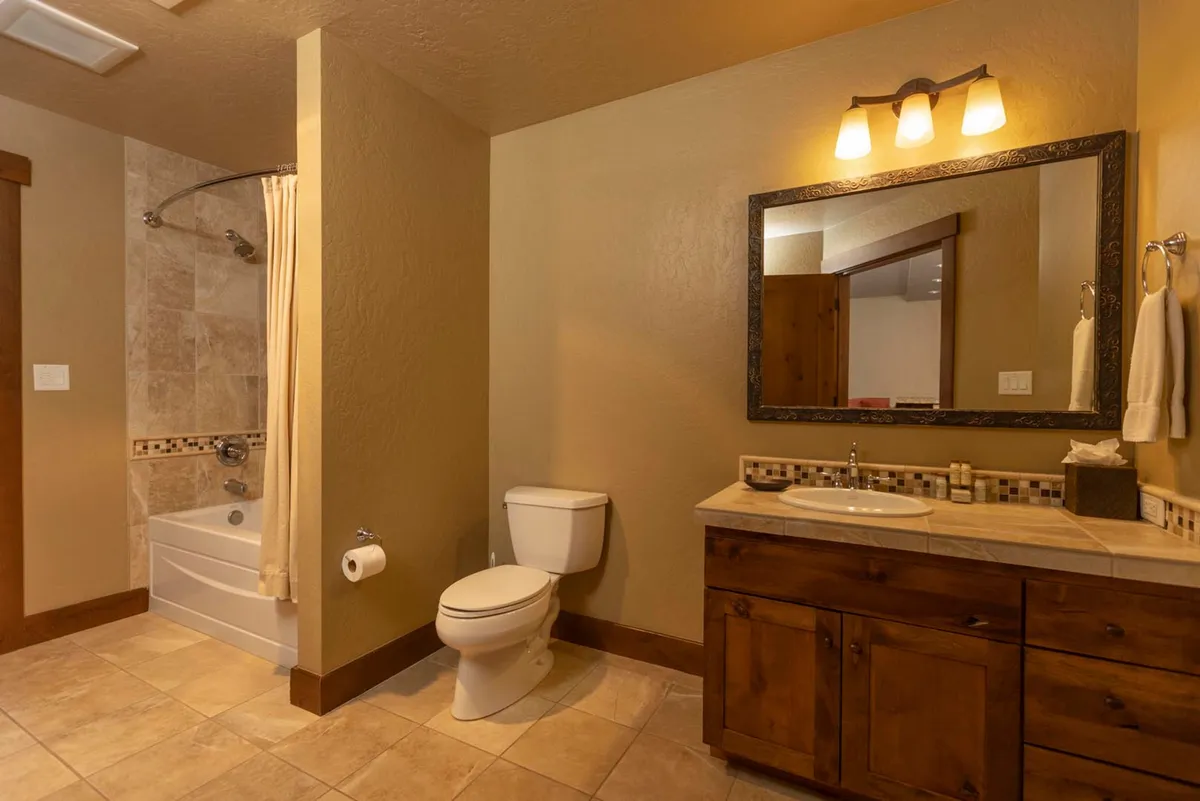 This image features a pristine bathroom with a spacious vanity, a large framed mirror, and a luxurious bathtub adjacent to a modern shower area. The tranquil, clean atmosphere invites relaxation and self-care, suggesting a spa-like environment within the property.