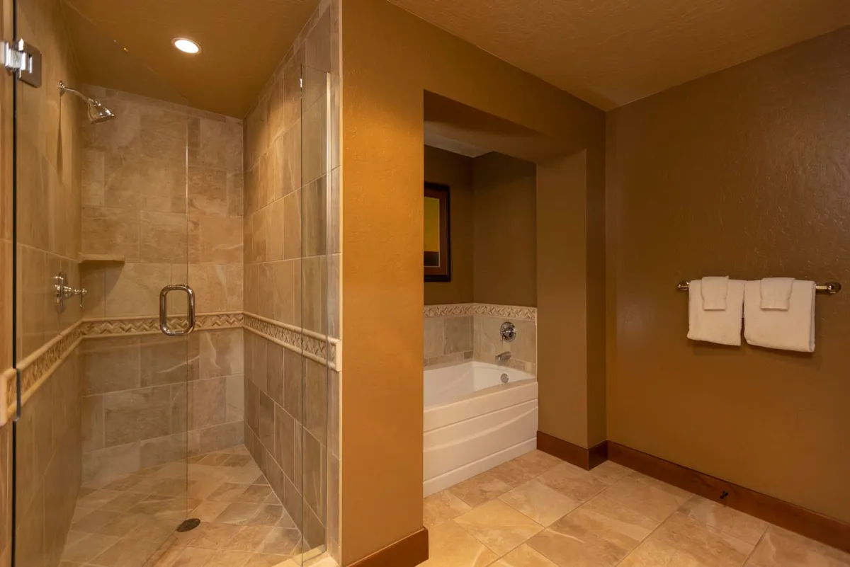 A luxurious bathroom scene with a glass-enclosed shower, inviting bathtub, decorative tile work, and plush towels, capturing a peaceful and rejuvenating mood.